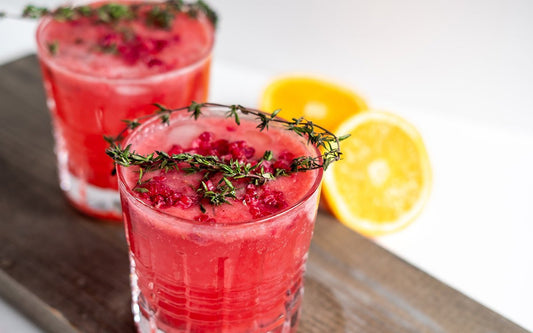 Zwei Gläser mit rotem Drink und Rosmarin und Zitronen-Garnitur. 