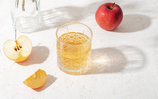 Frische Äpfel und Apfelessig in einem Glas mit Wasser verdünnt