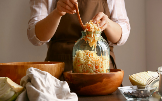 Person füllt Sauerkraut in ein großes Glas