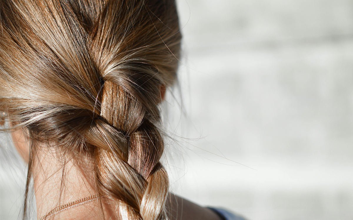 gesunde, blonde Haare zu einem Zopf gebunden