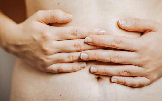 Person drückt Hände auf ihren Unterbauch.