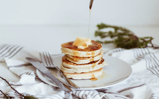Gestapelte Pancakes auf einem grauen Teller mit Besteck